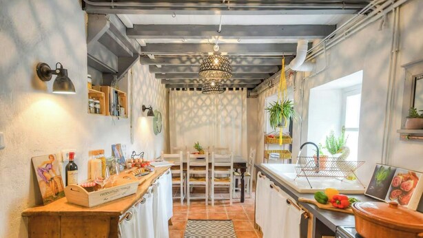 A kitchen with a wooden counter, a stove, a hanging light fixture, and a window with plants. - Riverside house with farm animals in Béarn (Autevielle-Saint-Martin-Bideren)