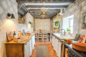 Een keuken met een houten aanrecht, een fornuis, een hanglamp en een raam met planten.
