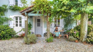 A house with a covered porch, a dog, and a person sitting at a table. - Riverside house with farm animals in Béarn (Autevielle-Saint-Martin-Bideren)