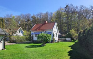 A white house with a red roof, a blue-striped awning, and a well-maintained lawn. - Stunning home in Billdal with WiFi (Billdal)