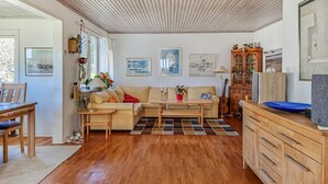 Una sala de estar con sofá, mesa de centro, aparador de madera y obras de arte en las paredes.