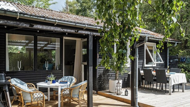 Een houten terras met buitenmeubilair, een barbecue en een overdekte patio.
