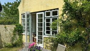 A wooden table with chairs, a flower pot, and a window with open shutters. - Villa from 1917 high above Tisvildeleje (Tisvilde)
