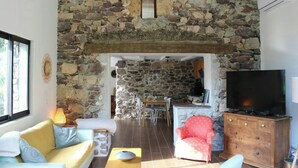 A stone-walled room with a television, a red armchair, and a sofa. - 17th century renovated barn in Valdeblore (Valdeblore)