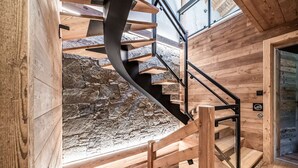 Eine Wendeltreppe mit Holzboden und Metallgeländern, die zu einer Steinwand und einer Holztür führt.