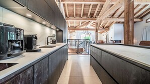 Eine Küche mit einer modernen Espressomaschine, Holzbalken und Blick auf einen Balkon.