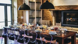 A dining table set for six with clear chairs, a fireplace, and pendant lighting. - Large 16th century farm estate in Dordogne (Sainte Croix)