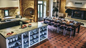 A rustic kitchen with a central island, a dining area with chairs, and a fireplace. - Large 16th century farm estate in Dordogne (Sainte Croix)