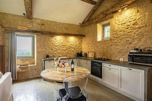 Une cuisine rustique avec des murs en pierre, une table à manger en bois et des appareils électroménagers modernes.