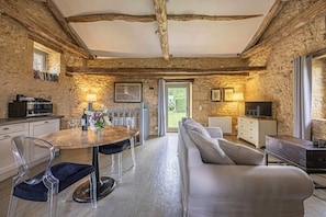 A rustic stone interior with a dining area, sofa, and TV. - Large 16th century farm estate in Dordogne (Sainte Croix)