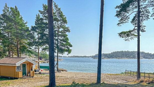A cabin by a lake with a dock, surrounded by tall trees. - Beautiful home in Nynäshamn with WiFi (Nynäshamn)