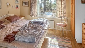 A bedroom with two beds, a chair, a nightstand, a lamp, and a window with curtains. - Beautiful home in Nynäshamn with WiFi (Nynäshamn)
