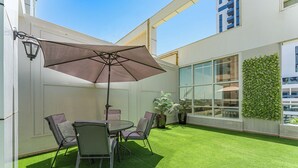 En terrasse med et bord, stole og en parasol.