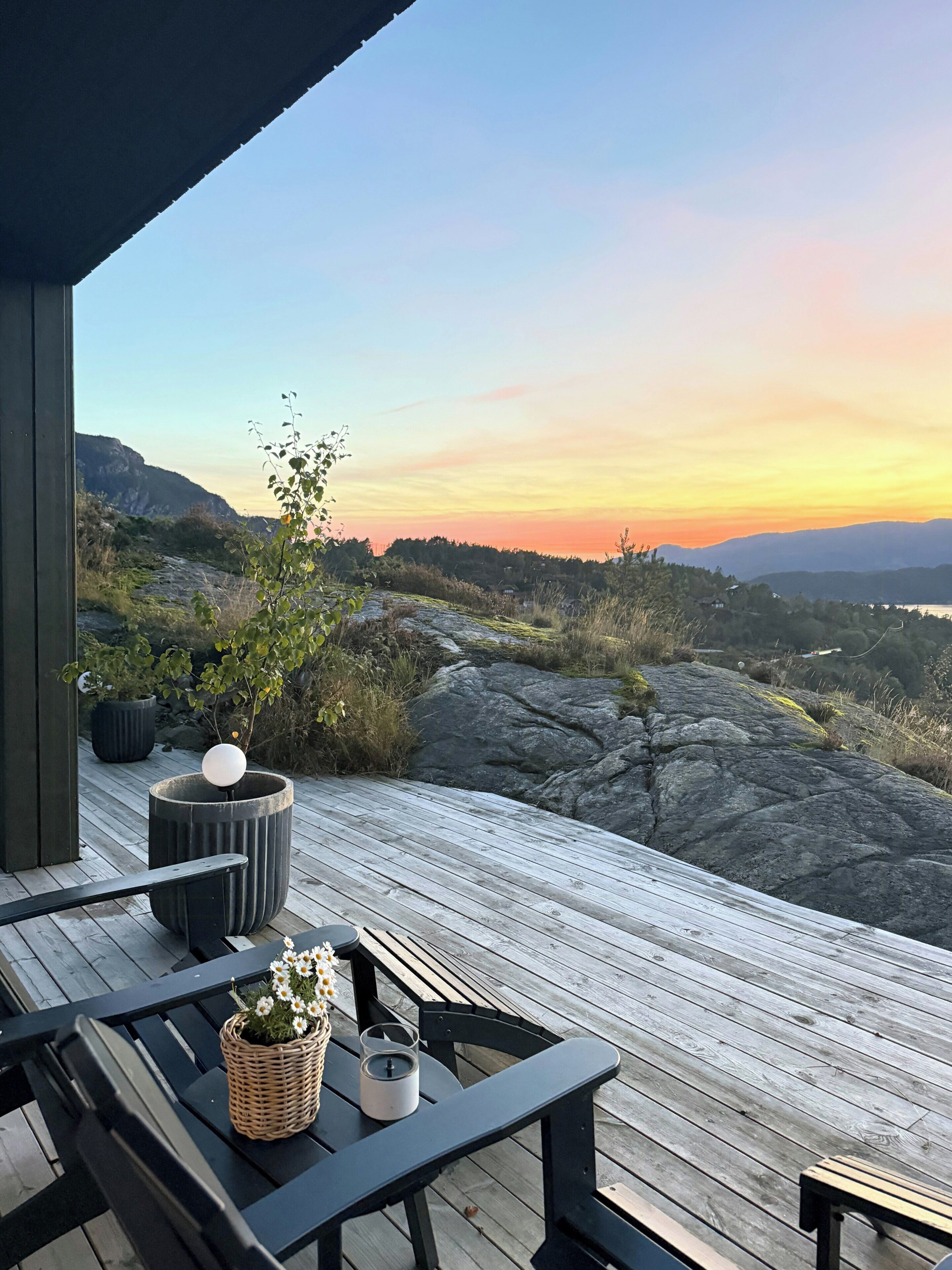 Una terraza de madera con vistas a terreno rocoso y montañas a lo lejos.