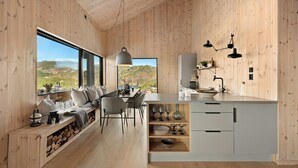 Eine moderne Küche mit Holzwänden, einem Essbereich mit Blick und einer eingebauten Sitzbank mit Stauraum.
