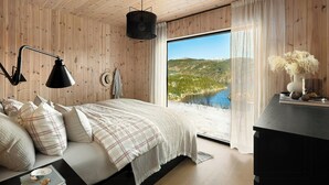 Ein Schlafzimmer mit einem großen Bett, einem Schreibtisch, Seeblick und Holzwänden.