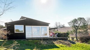 Ett modernt hus med ett stort fönster, en veranda och utemöbler.