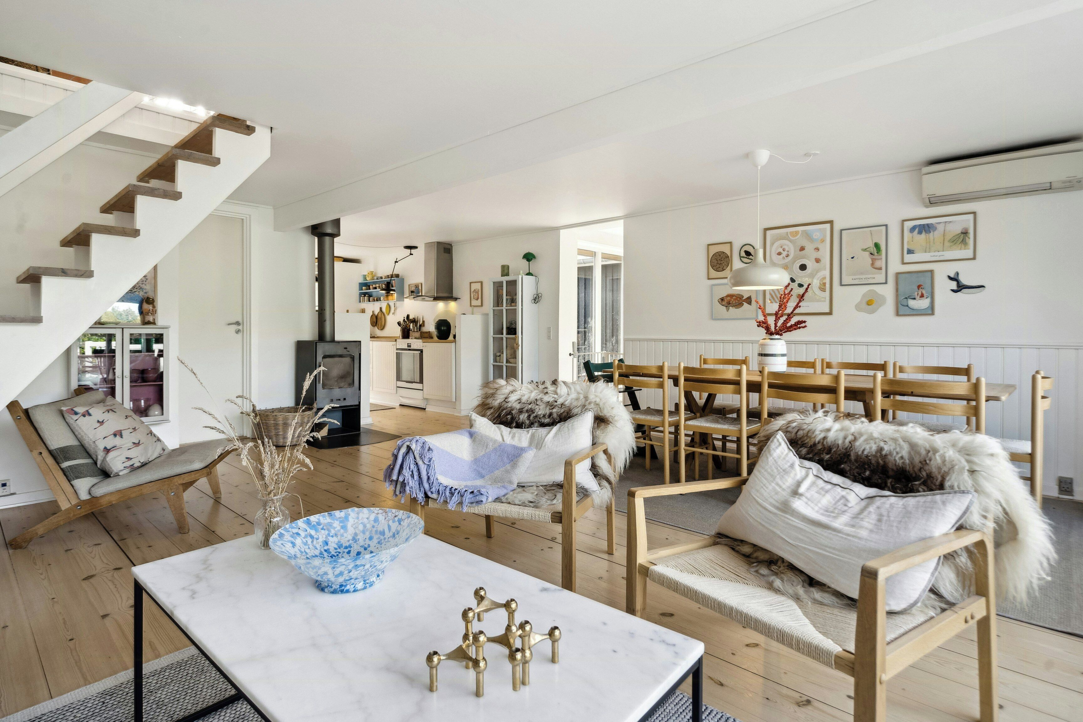 Een ruime woonkamer met een trap, houten meubels en een keuken op de achtergrond.