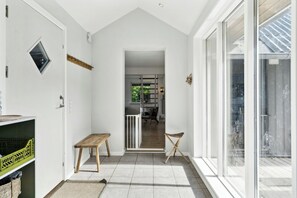 A hallway with a bench, a small table, and a door leading to a kitchen area. - Big family dream of a summer home (Ebeltoft)