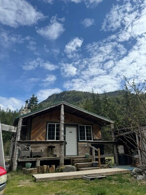 A rustic cabin with a wooden exterior, a front door, and a porch area.