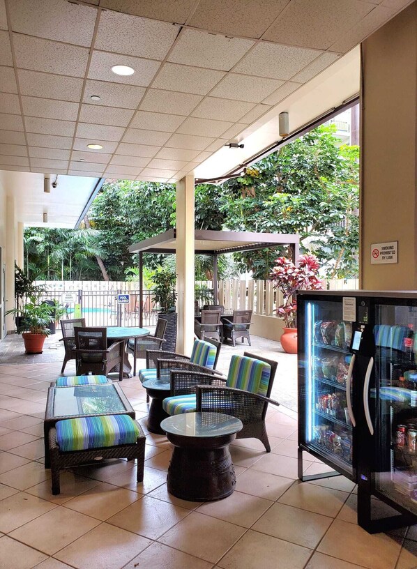 A covered outdoor seating area with wicker furniture and a vending machine.