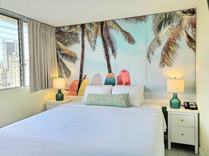 Une chambre d’hôtel avec un lit, deux tables de chevet, une fenêtre avec des rideaux, une vue sur la ville et une fresque murale représentant des palmiers.