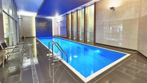 Piscina interior con agua cristalina, una escalera metálica y un cartel que indica una profundidad de 1.2 metros.