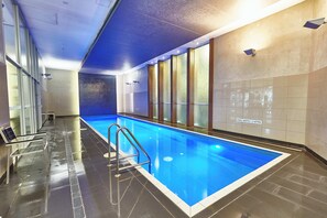 An indoor swimming pool with clear water, a metal ladder, and a sign indicating a pool depth of 1.2 meters. - Exclusive Stays - Mainpoint (Southbank)