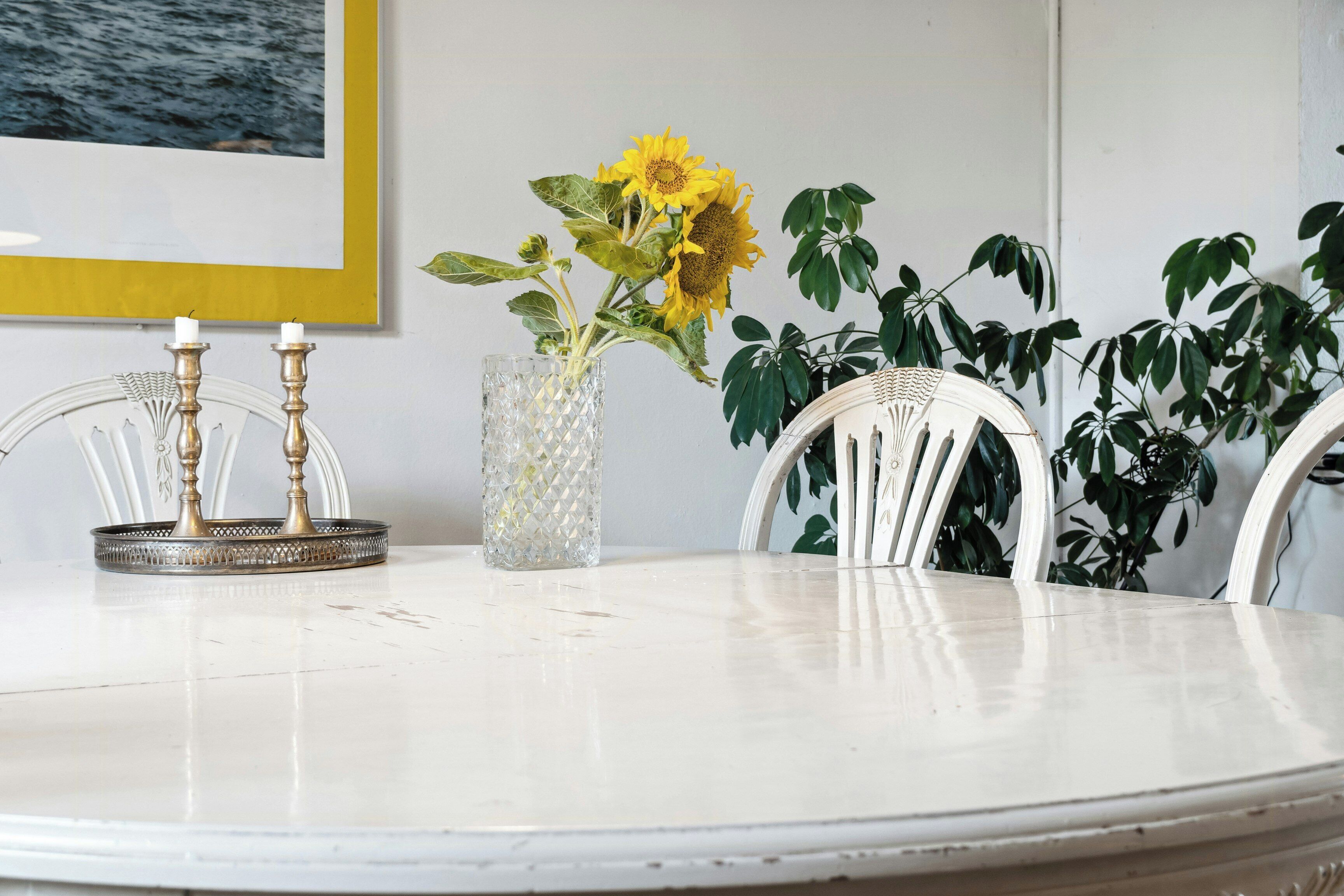 A round white table with a vase of sunflowers, a candle holder, and a framed picture on the wall. - Friends in small fishing home Betty Fjord (Harpelunde)