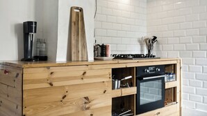 A kitchen with a wooden cabinet, a coffee maker, and a stove. - Friends in small fishing home Betty Fjord (Harpelunde)