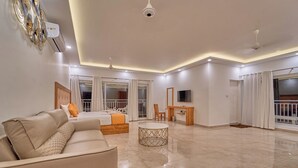 Amplia sala de estar con sofá, una mesita redonda y una cama con cortinas.