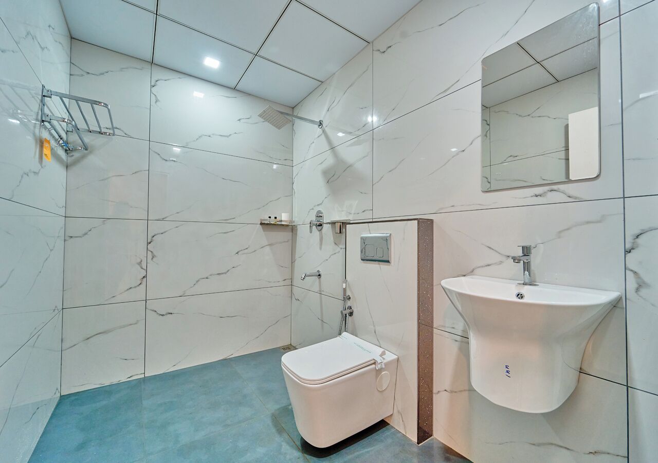 A bathroom with a toilet, sink, shower, and a mirror.
