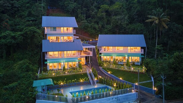 Un resort de varios pisos con piscina, rodeado de abundante vegetación.
