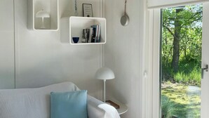 Ett modernt sovrum med en vit soffa, ett sidobord, en golvlampa och en bokhylla.