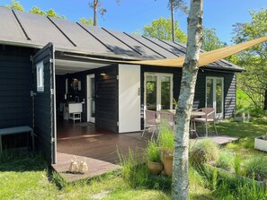 Una casa moderna con un patio, una zona de comedor y un pequeño jardín.