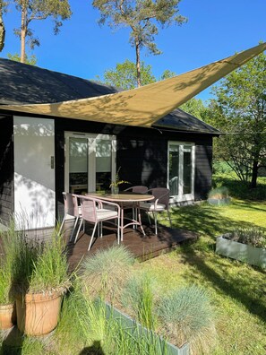 Una casa moderna con un patio, mobiliario exterior y un amplio ventanal.