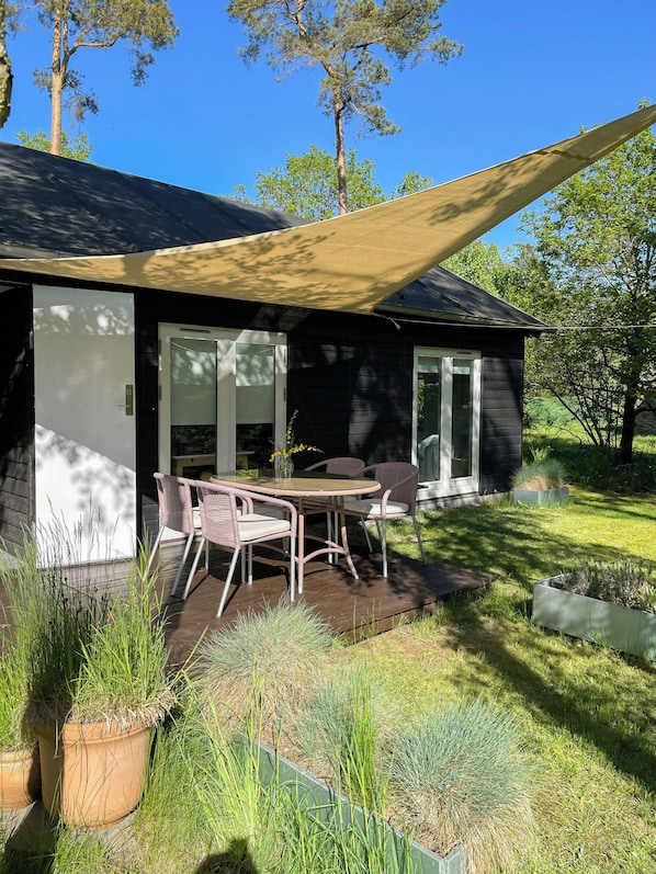 Una casa moderna con un patio, mobiliario exterior y un amplio ventanal.