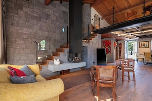 Ein großzügiger Wohnbereich mit Steinwand, Kamin, einer Couch und Holzmöbeln.
