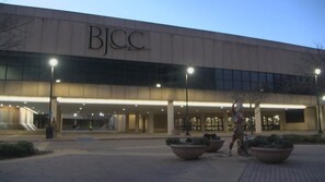 Un edificio con un letrero que dice 'BJCC' y un área de entrada cubierta con macetas grandes.