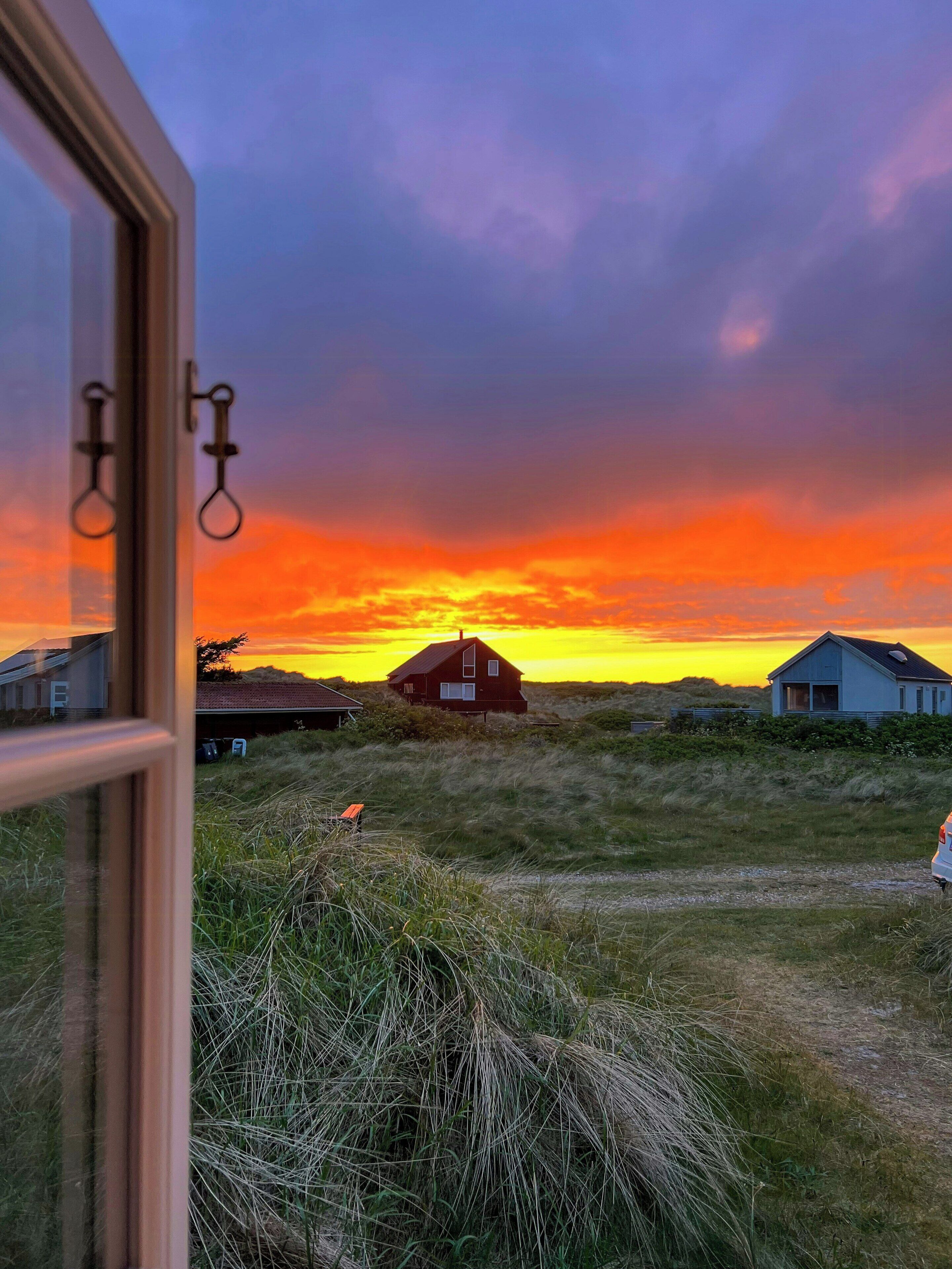 A rural landscape with houses and a sunset.