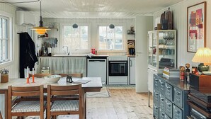 Eine geräumige Küche mit Holzböden, eine Essecke mit Tisch und Stühlen sowie ein Wohnbereich mit Sofa und Schrank.