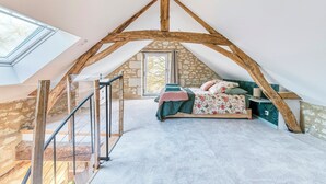 A bedroom with a sloped ceiling, stone walls, a bed with floral bedding, a nightstand, and a window. - Eco-cottage with bird sanctuary in Anjou (Brissac Loire Aubance)