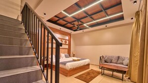 Un dormitorio con una cama, un sofá, un banco de madera y una escalera.