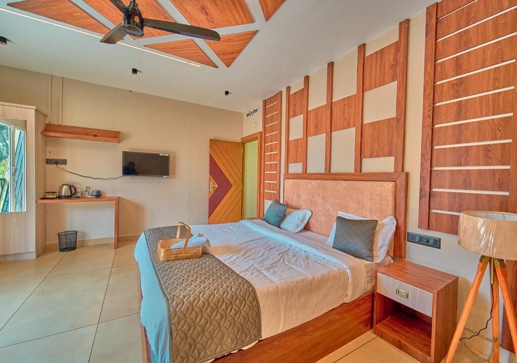 A bedroom with a bed, bedside table, lamp, TV, and a unique wooden wall design.