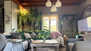 Un accogliente soggiorno con un divano verde, un tavolino in legno e una parete in pietra.