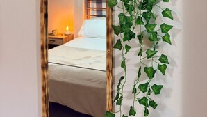 Una stanza con un letto, uno specchio e una pianta pensile.