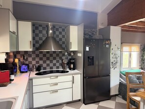 Una cocina moderna con un refrigerador de acero inoxidable, un horno empotrado y una campana extractora grande.