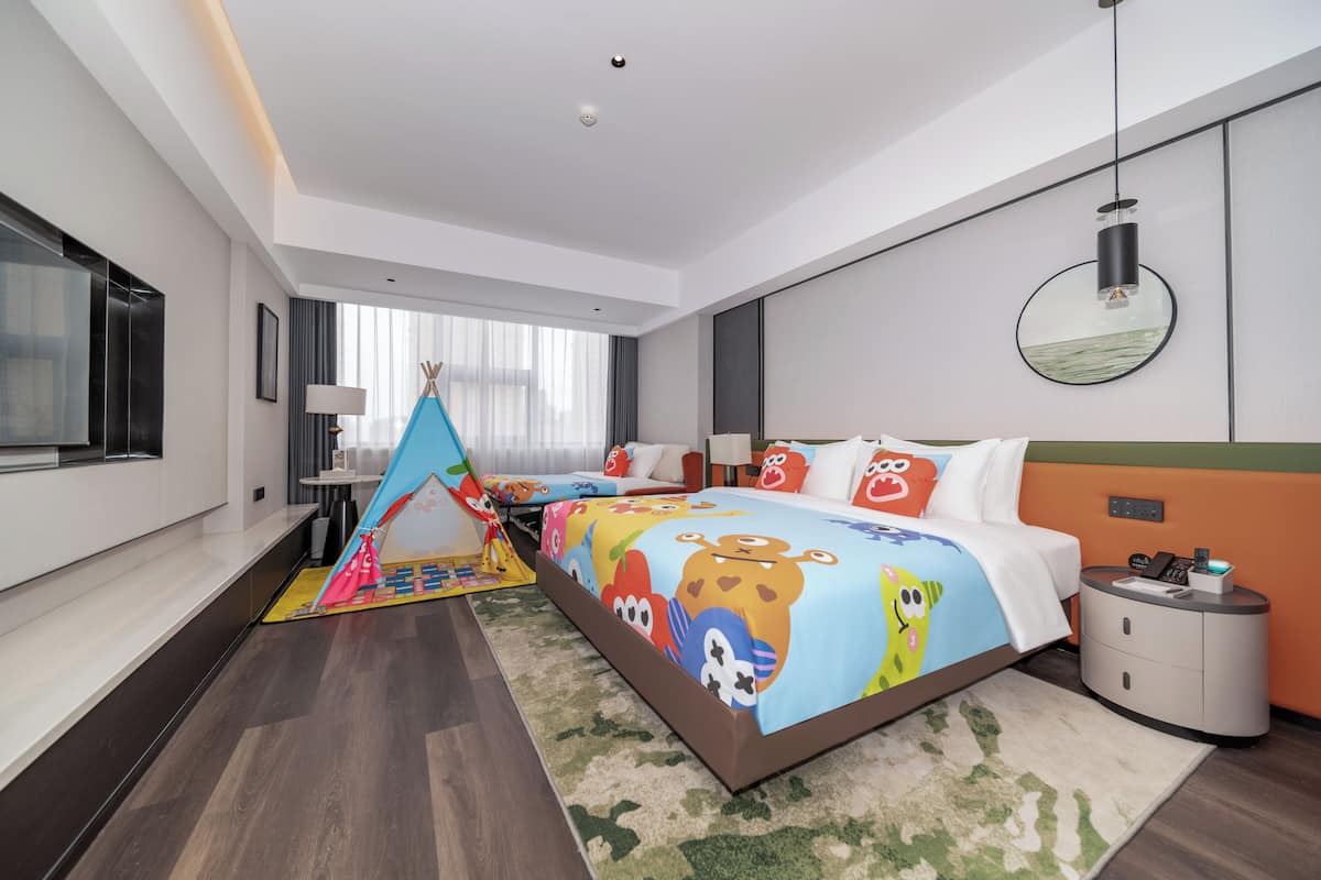 A hotel room with a large bed, a nightstand, a lamp, a mirror, and a window with curtains.