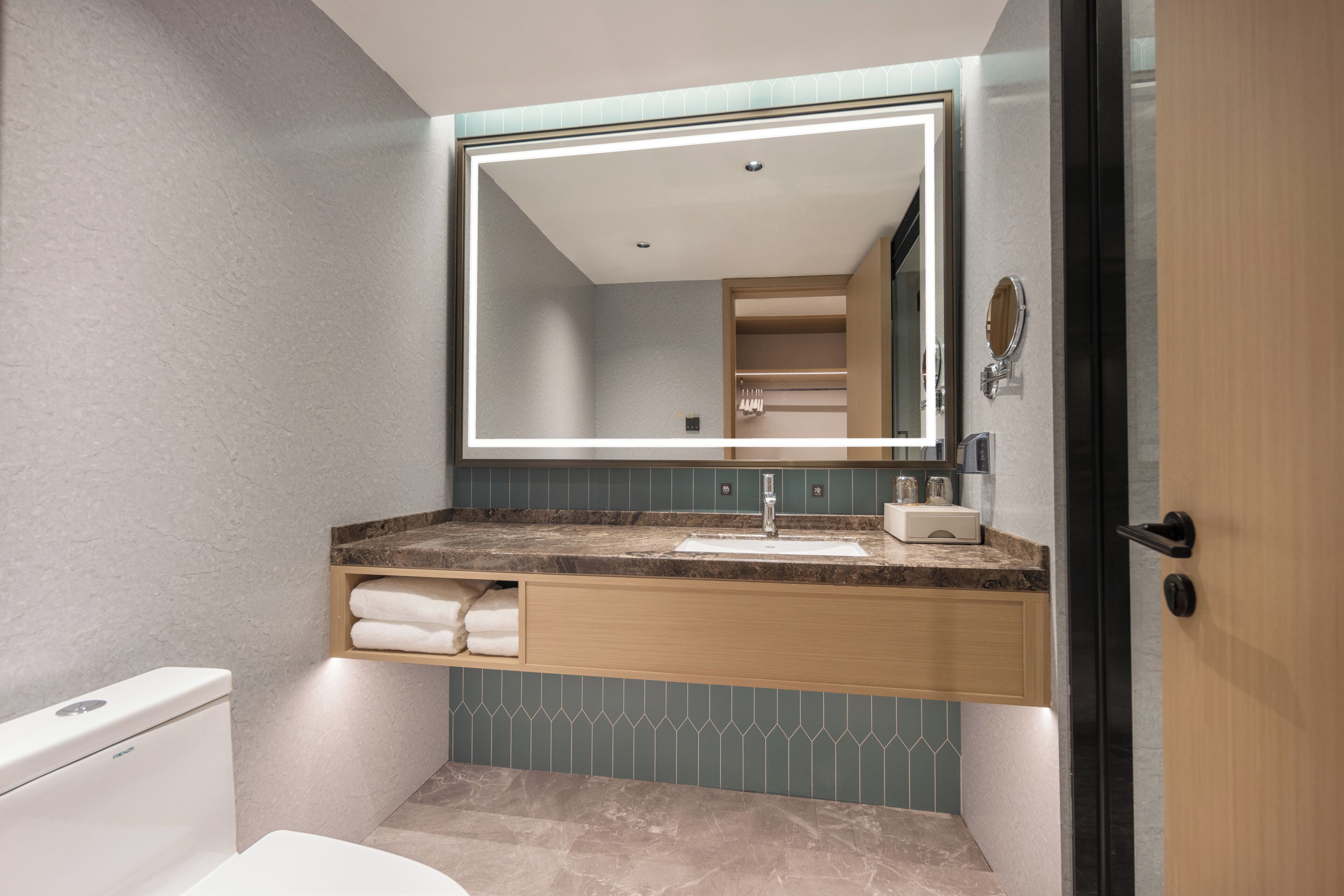 A bathroom with a toilet, a sink with a mirror above, and a towel rack.