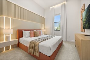 Ein modernes Schlafzimmer mit einem großen Bett, Nachttischlampen, einem Fernseher und Blick ins Freie.